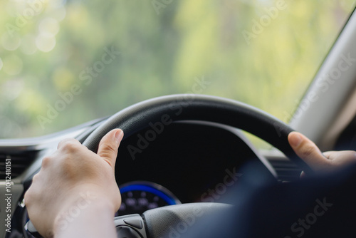Slika na platnu A young man's hand is held on the black steering wheel while he is driving in the car on a highway, a road trip travel concept