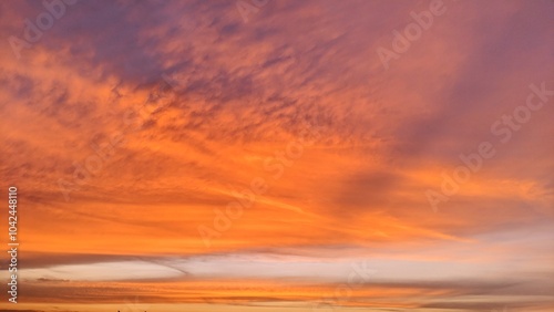 A dramatic sky with shades of orange, pink, and purple. The sky is divided into two distinct sections: a darker, purple area and a lighter, orange and pink area.