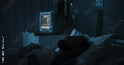 Man lies in hospital bed, eyes open, staring at ceiling.