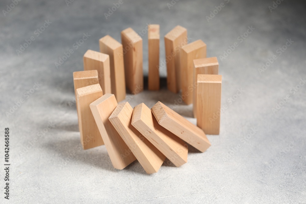 Domino effect. Wooden blocks falling on grey table, closeup Domino effect. Wooden blocks falling on grey table, closeup