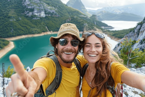 Happy hikers taking selfie on mountain hike with lake view - Smiling couple enjoying nature and adventure