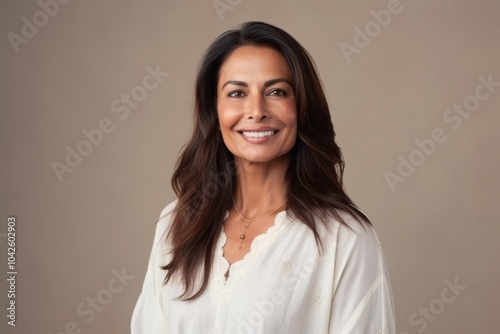 Portrait of a beautiful young woman smiling against a beige background