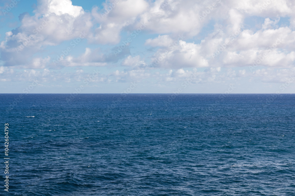 Obraz premium Seascape with blue sea and white clouds on blue sky.
