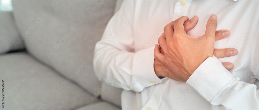 hand hold chest with heart attack symptoms, asian man working hard have chest pain caused by heart disease, leak, dilatation, enlarged coronary heart, press on the chest with a painful expression. hand hold chest with heart attack symptoms, asian man working hard have chest pain caused by heart disease, leak, dilatation, enlarged coronary heart, press on the chest with a painful expression.
