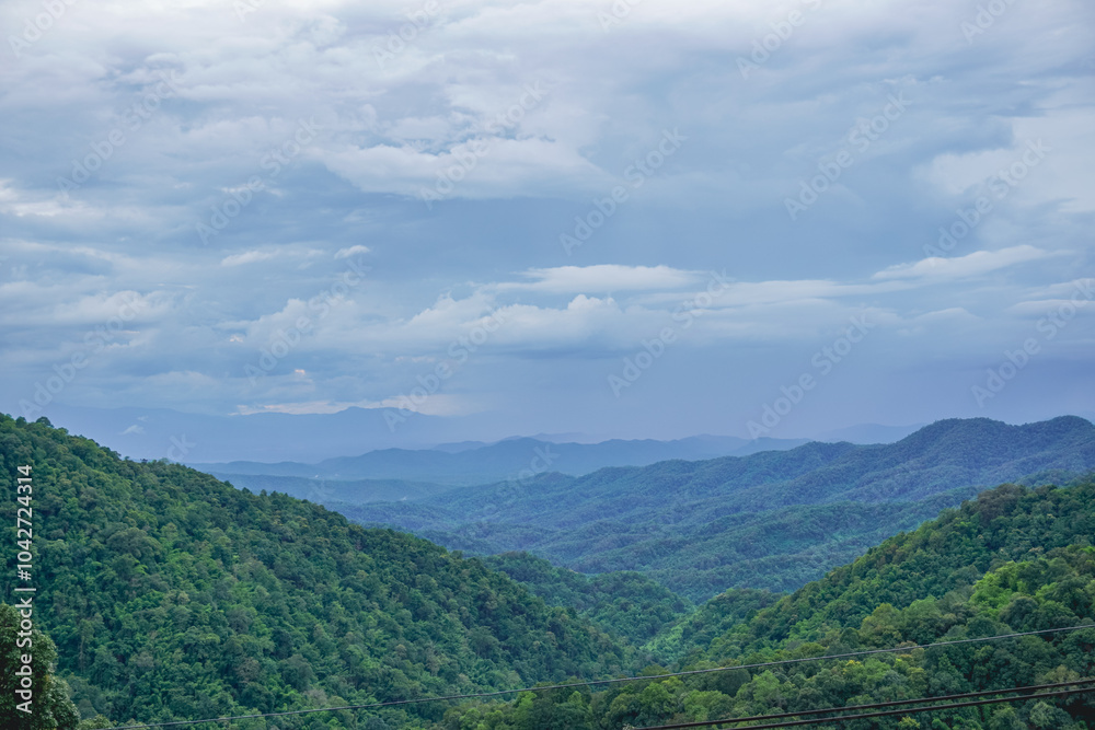 Obraz premium A beautiful landscape of the complex mountains range rolling over endlessly in a cloudy sky in Chiang Mai, Thailand. A symbol of relaxation holidays in winter up in the hill