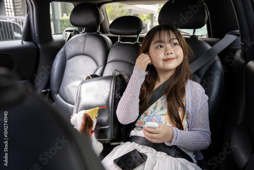 A young, adorable Asian girl is using her smartphone and listening to music