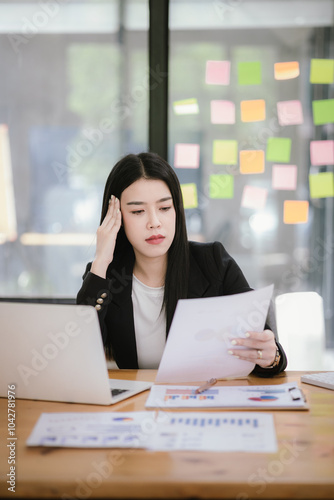 Image of Asian businesswoman working with laptop in home office. Beautiful woman sitting at desk, laptop, smartphone and documents on table.