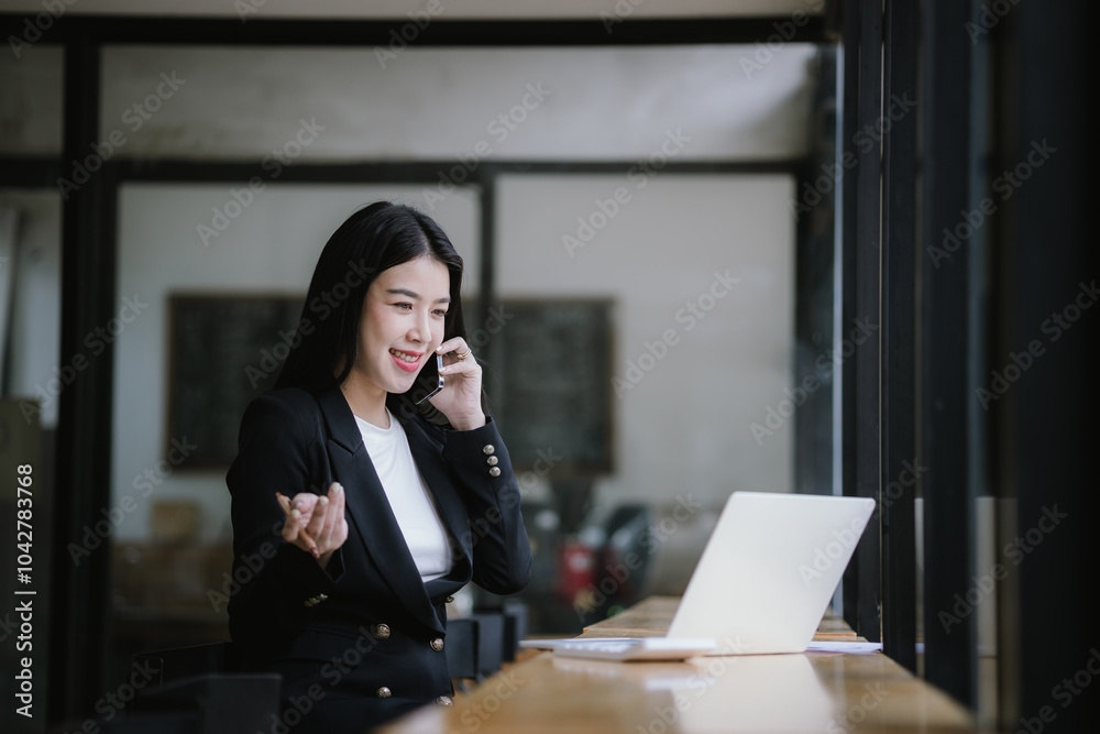 Beautiful Asian businesswoman talking on the phone using laptop in office Beautiful Asian businesswoman talking on the phone using laptop in office