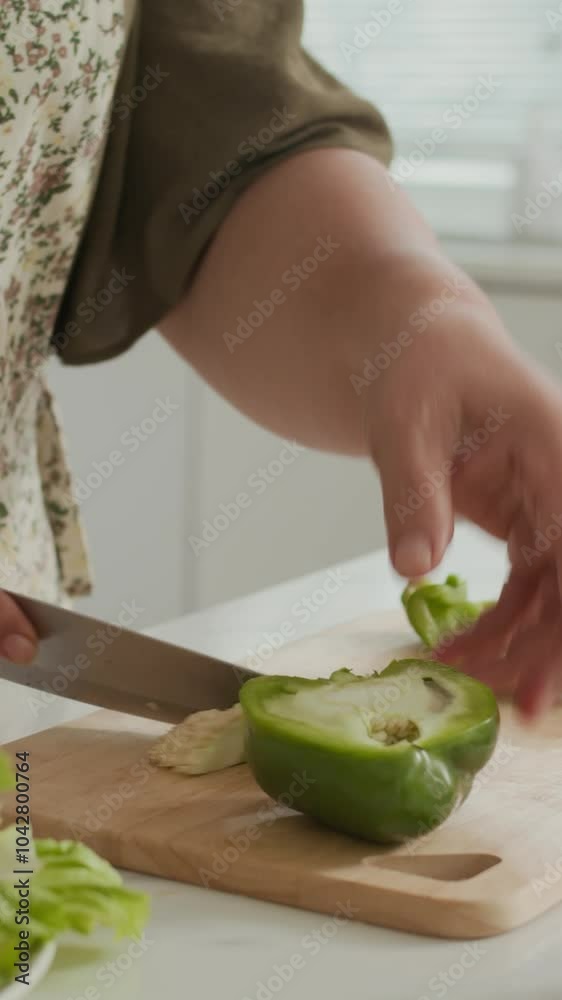 Vertical shot of unrecognizable housewife slicing bell pepper while cooking at home kitchen Vertical shot of unrecognizable housewife slicing bell pepper while cooking at home kitchen