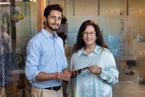 Shot of a two confident business persons talking in the work place. Two colleagues using a digital tablet while walking in a modern office photo