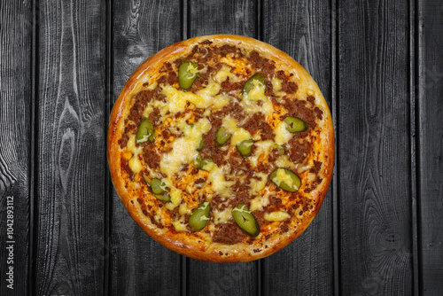 Hunter's pizza with minced meat, pickles and cheese, top view, on black wooden background.