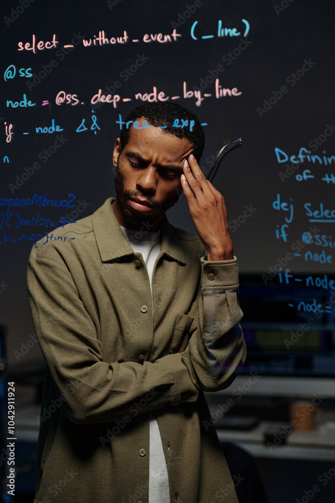Man reviewing coding script on digital screen in professional workspace while holding head in focus. Expression of concentration and depth in thinking Man reviewing coding script on digital screen in professional workspace while holding head in focus. Expression of concentration and depth in thinking