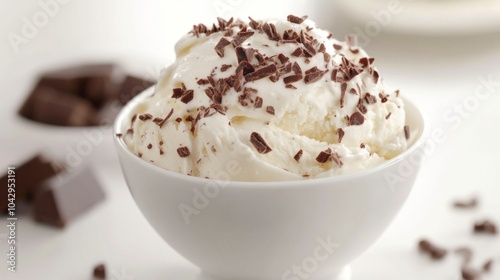 A bowl of vanilla ice cream topped with chocolate shavings, with chocolate squares in the background.