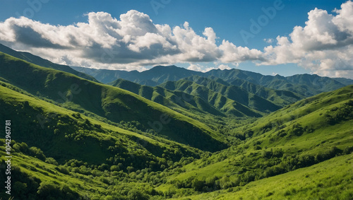 Lush green mountains under a bright blue sky with fluffy white clouds, creating a serene and open landscape.