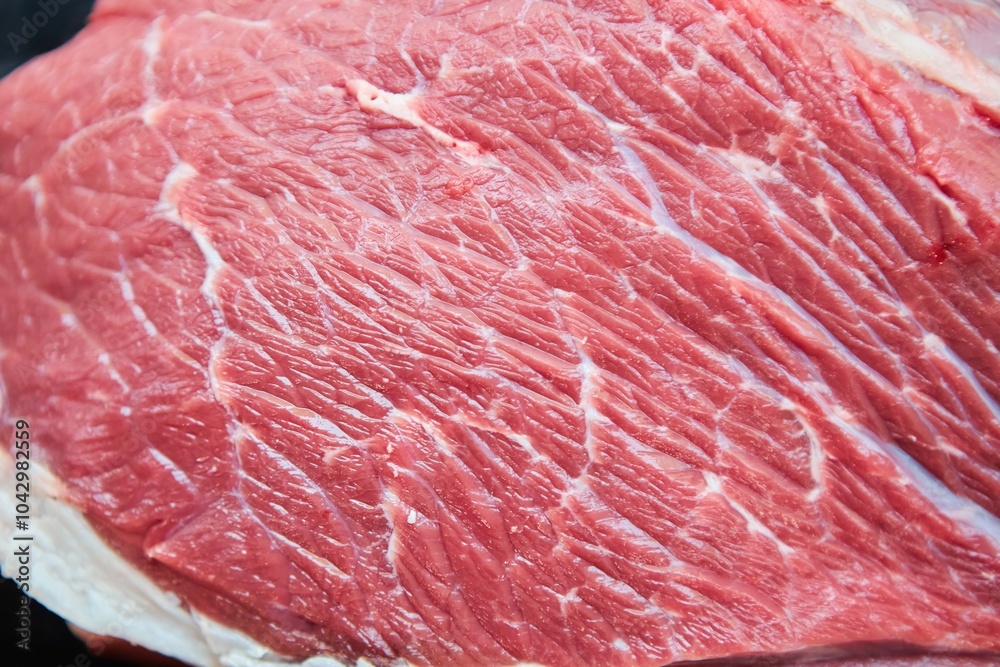 Raw meat lies on a dark background. Meat production. Raw meat lies on a dark background. Meat production.
