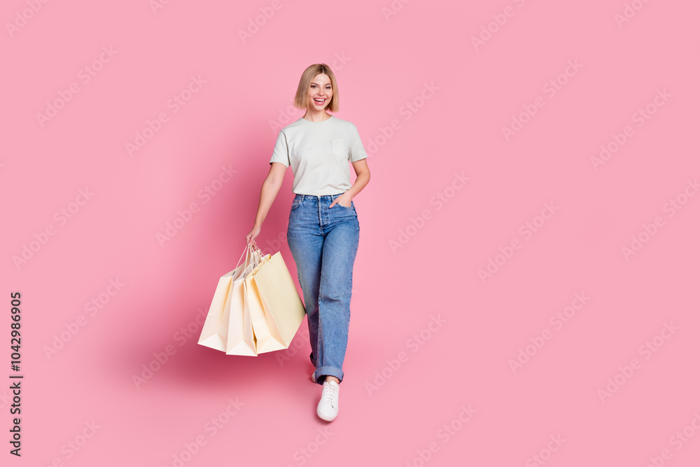 Photo of cheerful lovely girl wear stylish grey clothes hold carry bags isolated on pink color background Photo of cheerful lovely girl wear stylish grey clothes hold carry bags isolated on pink color background