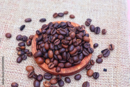 Robusta coffee beans or Coffea canephora in a wooden bowl and some scattered around it, close up view. photo