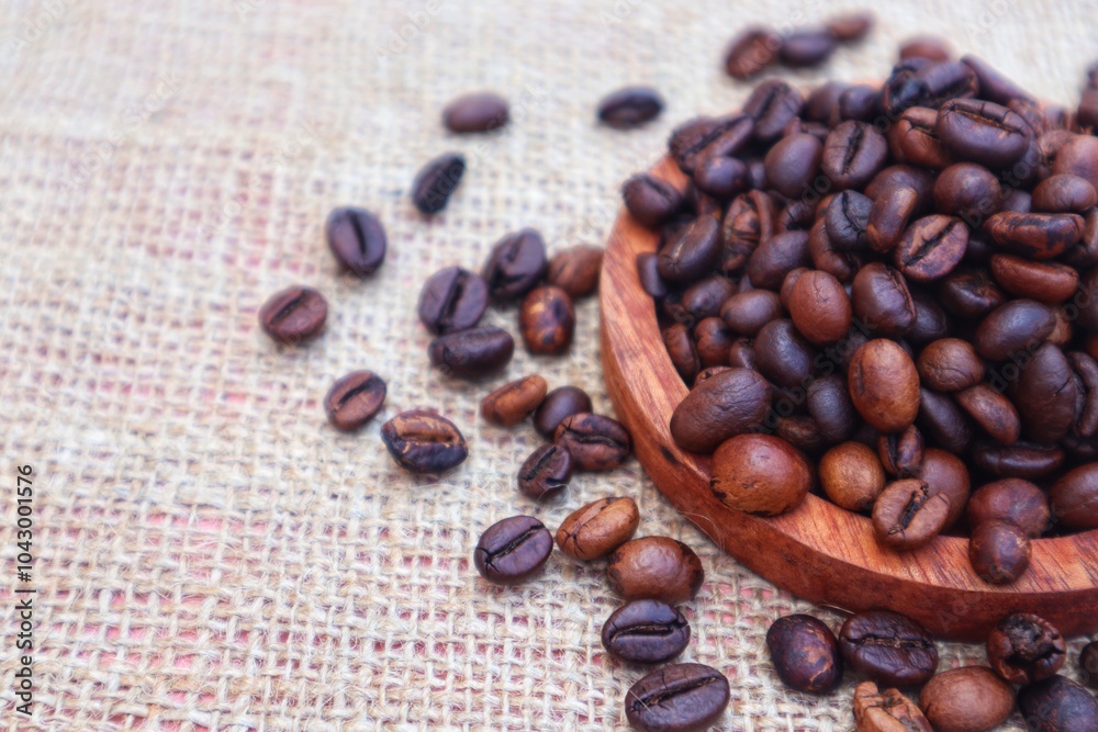 Robusta coffee beans or Coffea canephora in a wooden bowl and some scattered around it, close up view. Robusta coffee beans or Coffea canephora in a wooden bowl and some scattered around it, close up view.