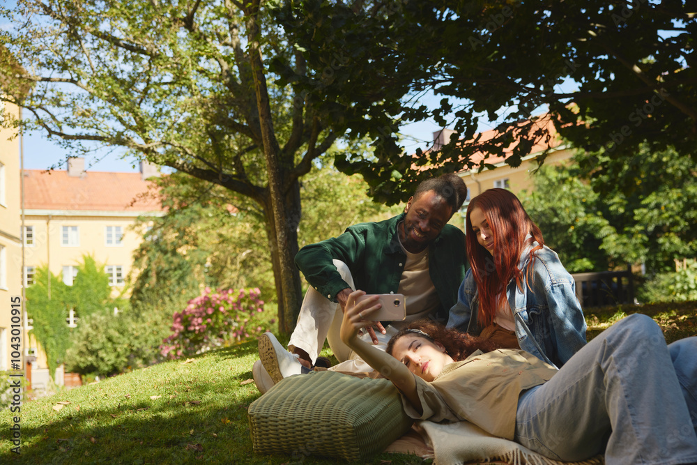 Group of young friends taking selfie while resting at park Group of young friends taking selfie while resting at park