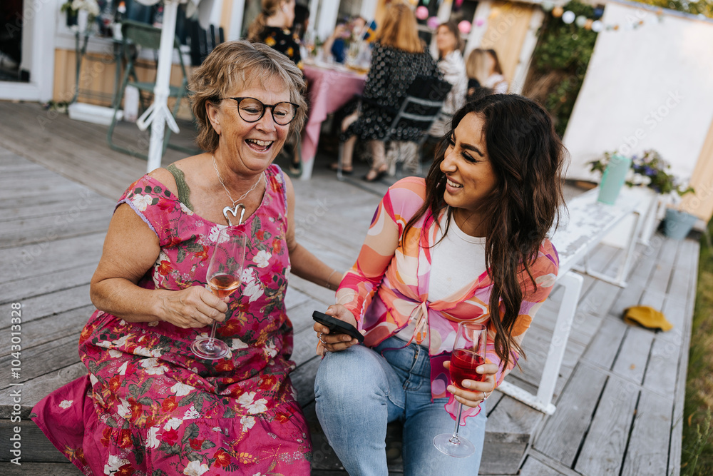 Cheerful senior woman talking to friend during party Cheerful senior woman talking to friend during party