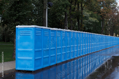 Row of blue toilets outside in the summer. photo