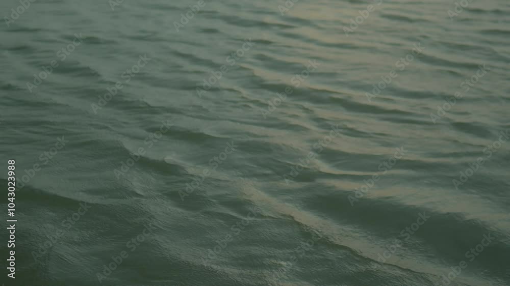 Close-up view of a calm ocean surface with subtle ripples and a muted green color. The water appears peaceful and tranquil, reflecting the soft light of the sky. Close-up view of a calm ocean surface with subtle ripples and a muted green color. The water appears peaceful and tranquil, reflecting the soft light of the sky.