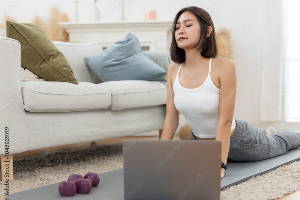 young asian female arm shoulder stretching practicing yoga with laptop sitting on floor in living room at home. Relax and stretch and workout morning at home. Activity body movement exercises. young asian female arm shoulder stretching practicing yoga with laptop sitting on floor in living room at home. Relax and stretch and workout morning at home. Activity body movement exercises.