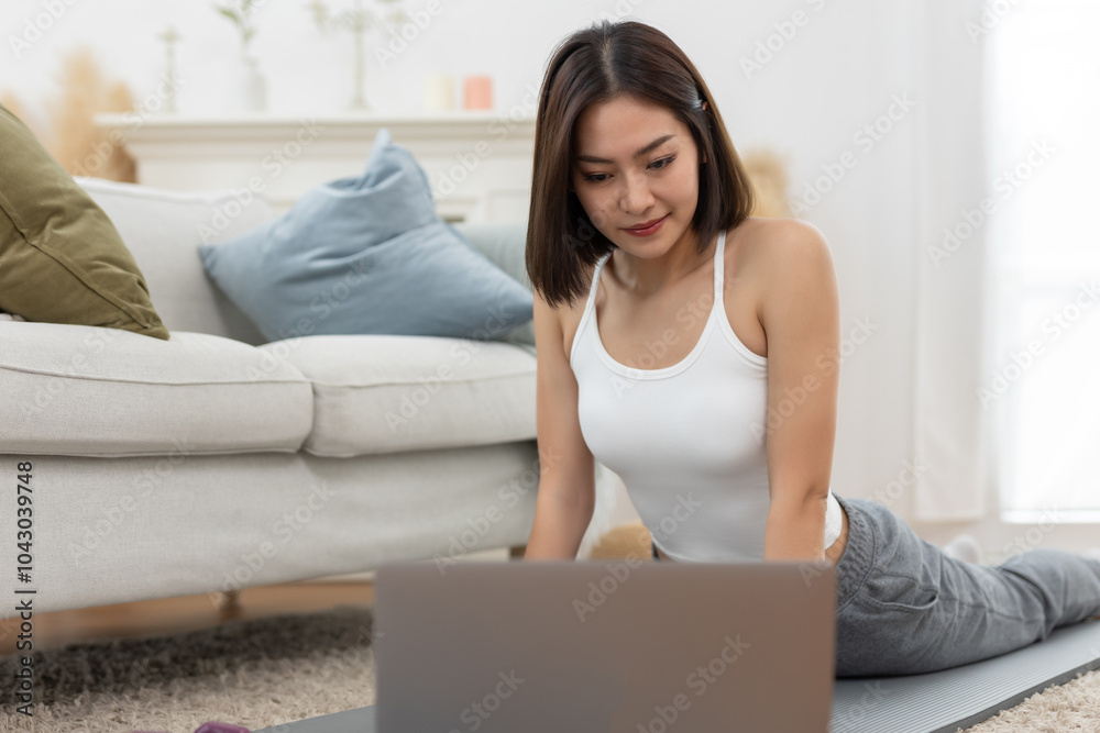 young asian female arm shoulder stretching practicing yoga with laptop sitting on floor in living room at home. Relax and stretch and workout morning at home. Activity body movement exercises. young asian female arm shoulder stretching practicing yoga with laptop sitting on floor in living room at home. Relax and stretch and workout morning at home. Activity body movement exercises.