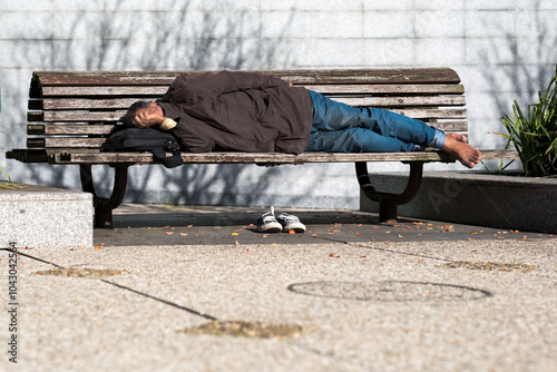 Un homme sans domicile fixe qui dort sur un banc public