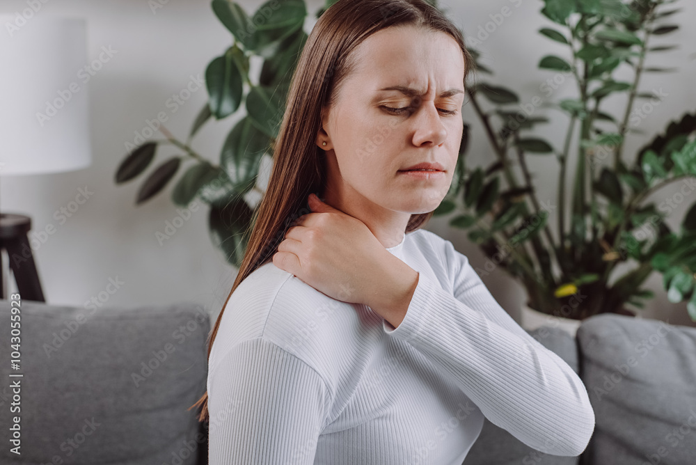 Close up of tired unhappy young woman feeling exhausted and suffering from neck pain, sad unhealthy caucasian doing massage sitting alone on grey couch at home. Health concept Close up of tired unhappy young woman feeling exhausted and suffering from neck pain, sad unhealthy caucasian doing massage sitting alone on grey couch at home. Health concept