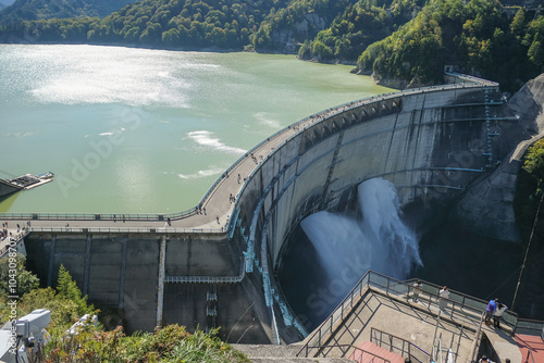 Kurobe Dam, Tateyama, Toyama, Chubu, Japan A scenic view of a dam, with water flowing over the edge photo