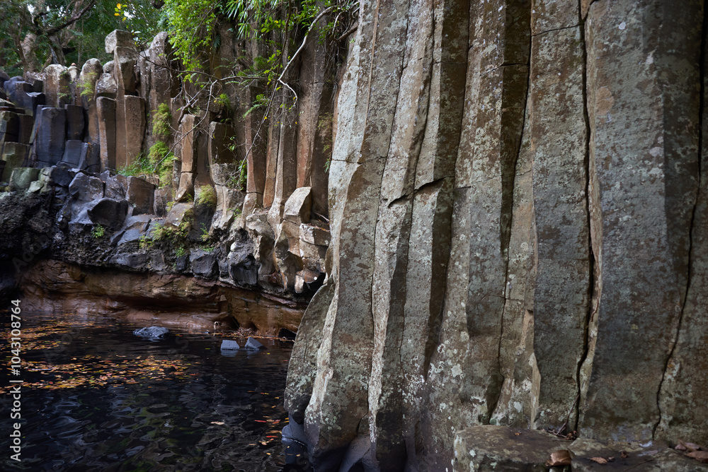 Fototapeta premium Close-up view of striking basalt rocks near a waterfall, featuring unique hexagonal patterns formed by ancient volcanic activity