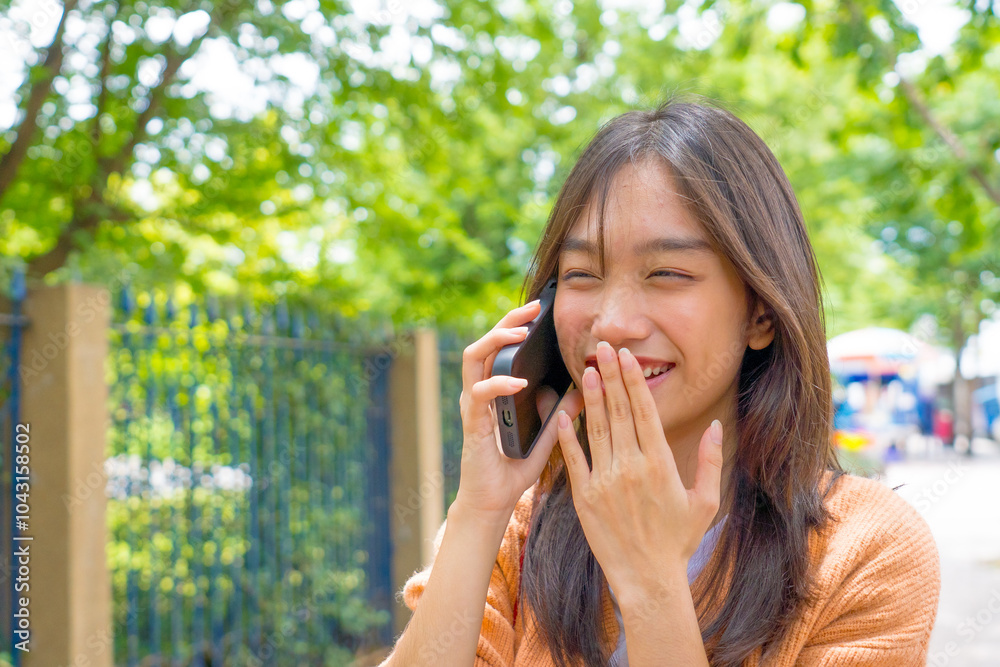 Asian young woman talking on cellphone smiling laughing while walking outdoors in city. Asian young woman talking on cellphone smiling laughing while walking outdoors in city.