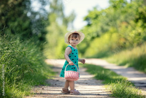 Little girl walking with picnic basket on dirt road in rural area