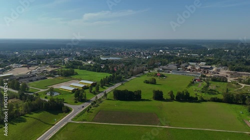 4K. Aerial view of an industrial area on the outskirts of a Dagda town, with green fields, roads, and scattered buildings, blending rural and urban landscapes. photo