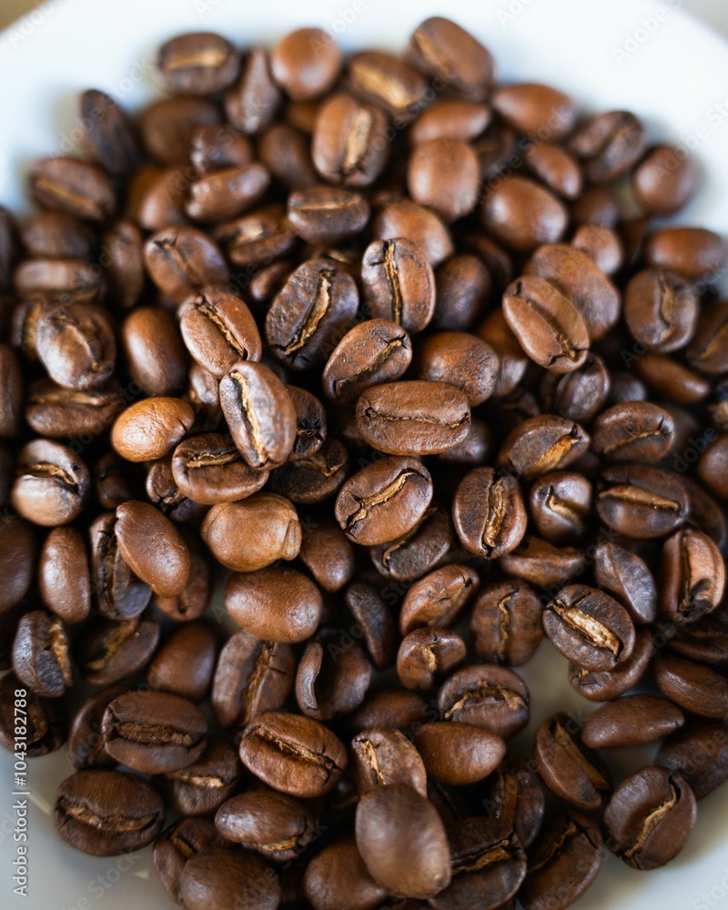 Naklejka premium Close-up of roasted coffee beans in a white bowl, showcasing rich brown tones and textures