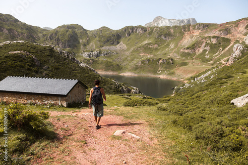 Man hiking towards a mountain lake in Asturias, Spain