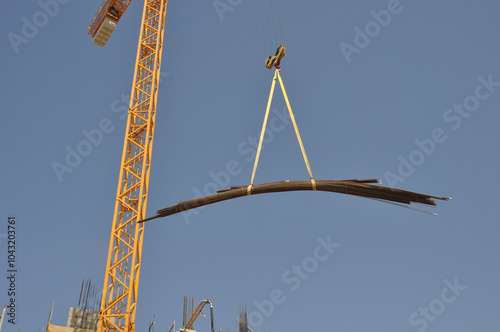 Crane Lifting Steel Beams at Construction Site
