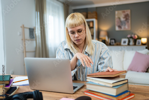 Young concentrated serious freelance business expert woman working at home office on laptop computer. Finance and economy professional worker having home work to finish calculations for client.