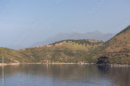 Scenic view of Porto Palermo Bay surrounded by majestic Ceraunian mountain range in Vlore, Albania. Calm turquoise Ionian Mediterranean sea. Rolling hills reflecting in idyllic lagoon. Coastal village photo