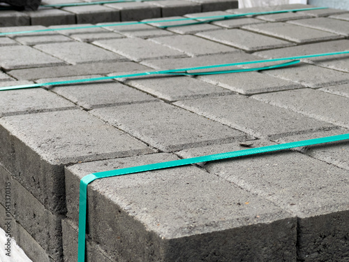 Stacked neatly, gray brick pavers are prepared for sidewalk installation in an urban area, showcasing the materials used in paving projects