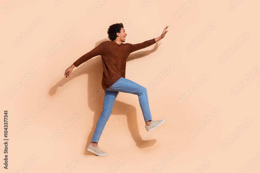 Joyful young african american man jumping against beige background wearing casual clothes showcasing his vibrant energy Joyful young african american man jumping against beige background wearing casual clothes showcasing his vibrant energy
