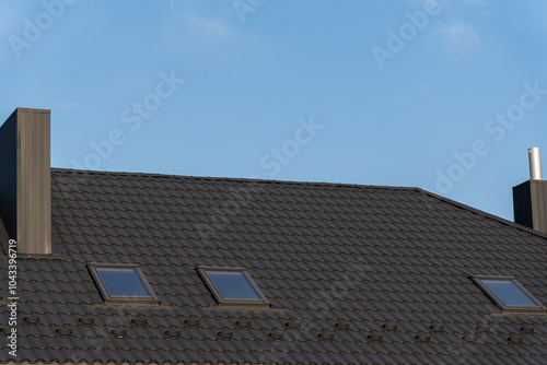 The rooftop displays freshly laid tiles with two skylights, enhancing natural light. The clear sky above highlights the modern roofing style and craftsmanship