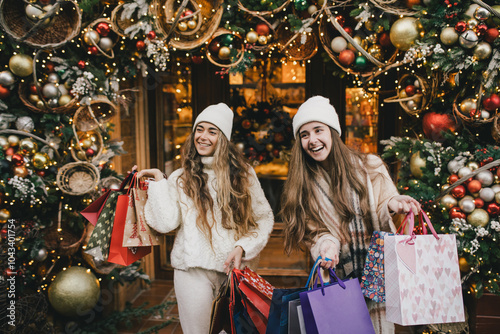 Foto Two young women enjoying Christmas shopping on a decorated street