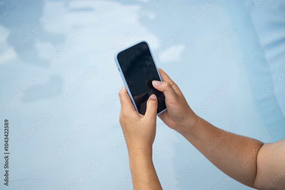 Young woman hand holding a white-screen smartphone mockup, working outdoors on blue background. People and technology concepts. High quality photo Young woman hand holding a white-screen smartphone mockup, working outdoors on blue background. People and technology concepts. High quality photo