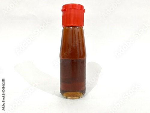 A glass bottle of sesame seed oil with red flip bottle top cap isolated on white background