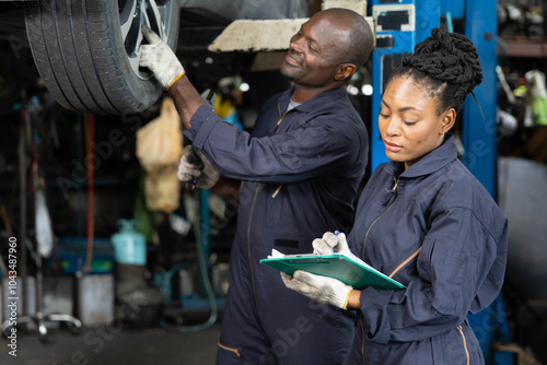 African mechanic workers fixing and checking a car or tire in automobile repair shop