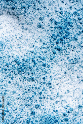 Background and pattern. White soap foam with bubbles, texture on blue tile background.