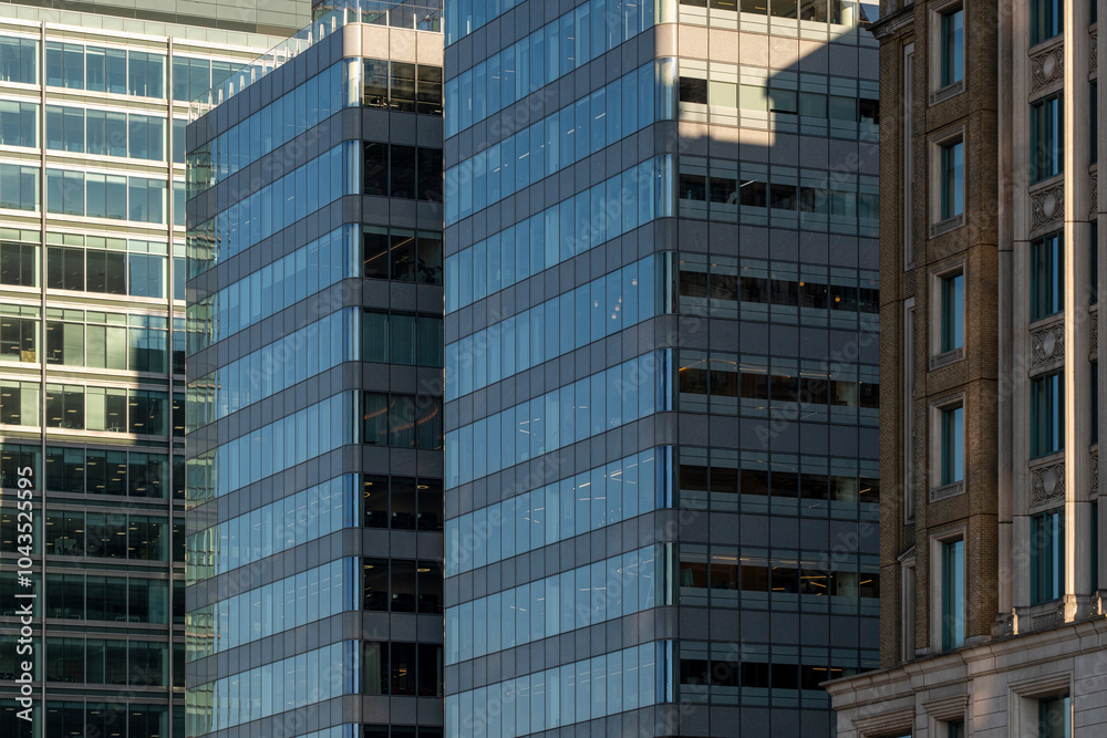 An urban scene with multiple skyscrapers showcasing reflective blue glass windows, representing the bustling energy and grandeur of a modern city. An urban scene with multiple skyscrapers showcasing reflective blue glass windows, representing the bustling energy and grandeur of a modern city.