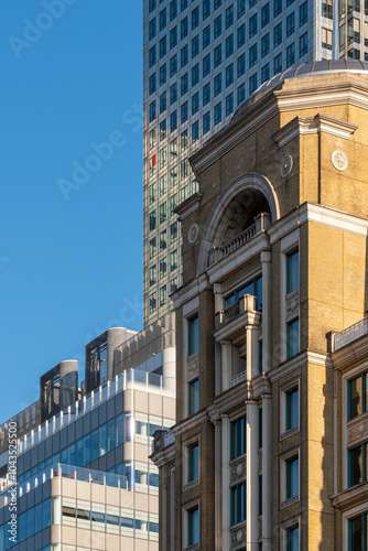 A classical building facade stands near modern skyscrapers in a bustling urban environment, mixing historical architecture with contemporary towers downtown in London UK